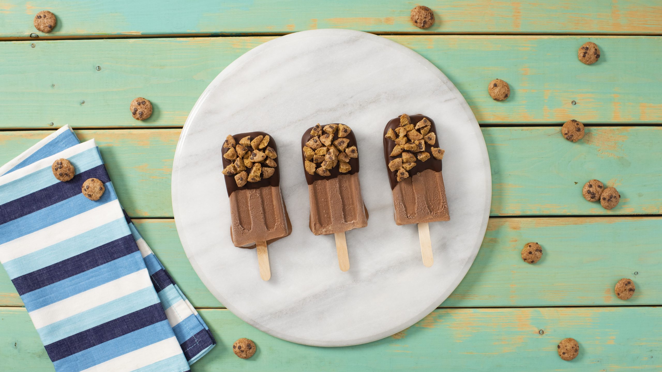 Chips Ahoy Cereal-Dipped fudgy ice pops on a white plate on a green background.