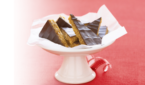 Honey Bunches of Oats Chocolate-Peanut Butter Bars cut into triangles sitting on a white platter on a red background.