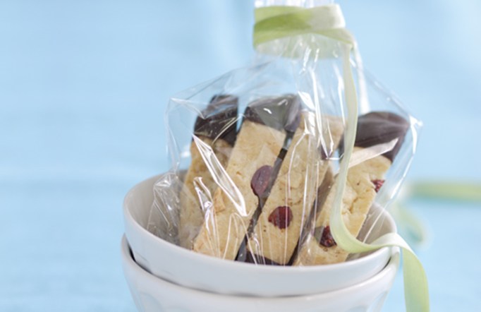 Cranberry Almond Crunch Chocolate-Cranberry Biscotti in a bowl wrapped in clear wrap with a green ribbon.