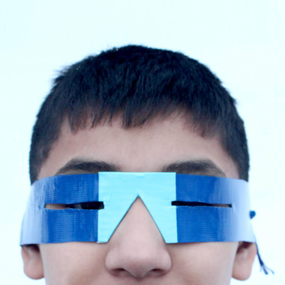 Child wearing blue paper snowgoggles craft.